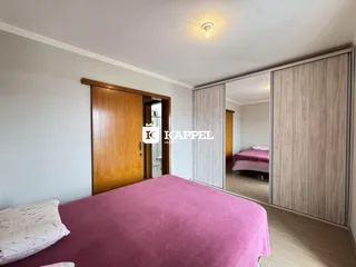 Quarto com cama rosa e armário de espelho em um ambiente interno.