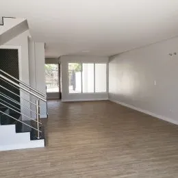 Ambiente interno com piso de madeira e escadaria visível em um imóvel.