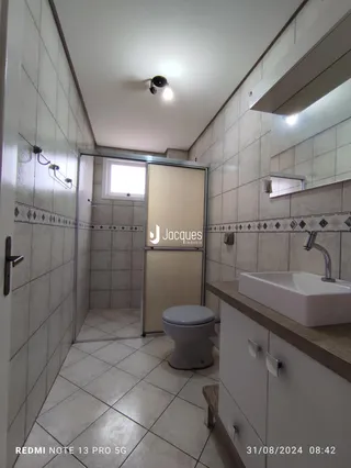 Interior de um banheiro com revestimento cerâmico e bancada.
