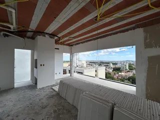 Interior de um espaço com teto exposto e vista da paisagem urbana.