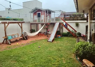 Vista do quintal de uma residência em Lajeado, Brasil, com gramado e estrutura de madeira.