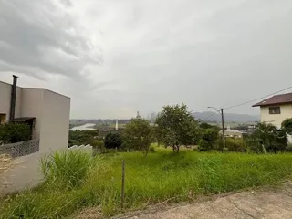 Vista externa de um terreno com vegetação e paisagem ao fundo.