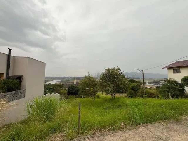 Vista externa de um terreno com vegetação e paisagem ao fundo.