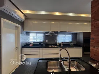 Cozinha moderna com armários brancos e bancadas escuras.