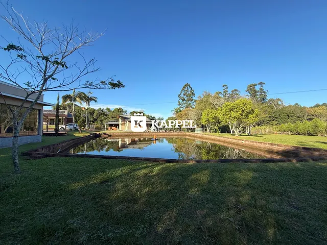 Vista externa de um terreno com gramado e um espelho d'água.
