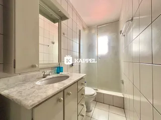 Banheiro com bancada de mármore e revestimento de azulejos brancos.