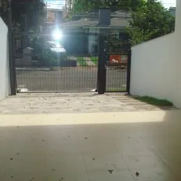 Vista da fachada da propriedade com portão de metal e área externa.