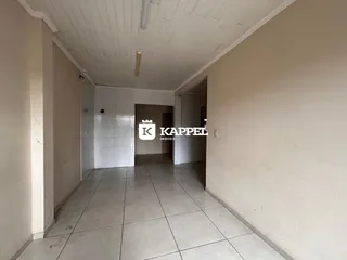Corredor interno com piso de cerâmica e teto de painel branco.