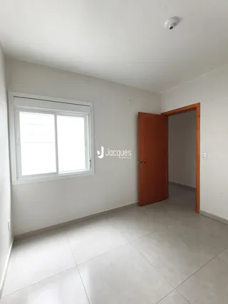 Vista interna de um ambiente com piso de cerâmica e porta de madeira.