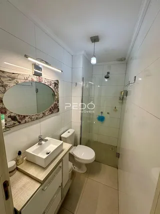 Banheiro com revestimento branco e box de vidro.