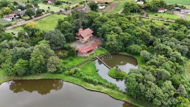 Vista aérea de uma residência cercada por vegetação e um corpo d'água em Lajeado.