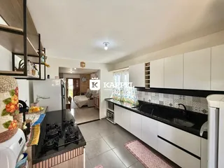 Uma cozinha moderna com armários brancos e bancadas escuras.