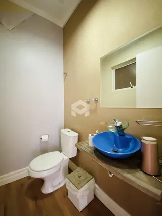 Banheiro com piso de madeira e pia azul.