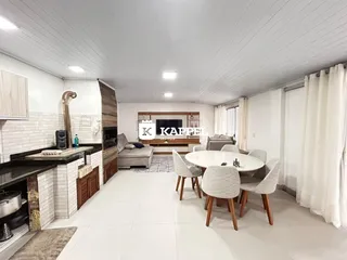 Sala de estar e cozinha integrada com piso claro e iluminação branca.