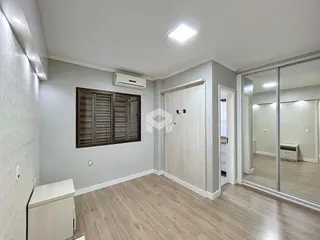 Quarto com piso de madeira clara e paredes cinzas.