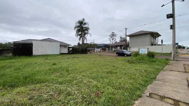 Vista externa de um terreno gramado com estruturas residenciais ao fundo.