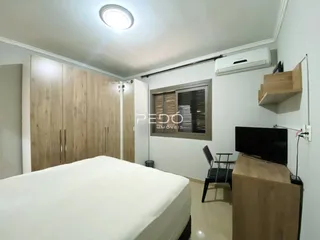 Quarto com armários de madeira e cama em um imóvel no Brasil.