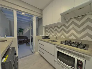 Cozinha moderna com armários brancos e bancada clara.