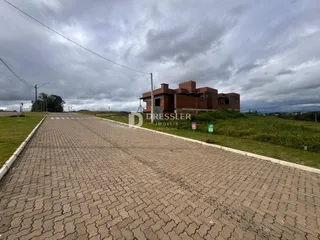 Vista da rua de terra em frente a uma residência de tijolos no campo.