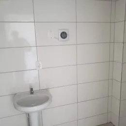 Parede de banheiro com azulejos brancos e um registro de pia.