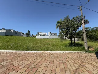 Vista externa mostrando uma área pavimentada e um campo gramado em frente a edifícios residenciais.