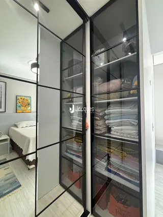 Quarto com cama e armários de vidro em um imóvel.