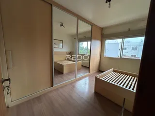 Quarto com piso de madeira e espelho grande em um imóvel no Brasil.