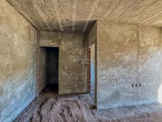 Imagem de um interior com paredes de concreto aparente e um vão de passagem.