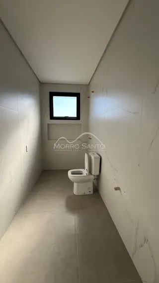 Foto de um banheiro com piso claro e paredes brancas em um corredor.