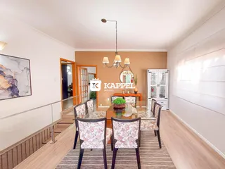 Foto de uma sala de jantar com mesa de madeira e cadeiras estampadas.
