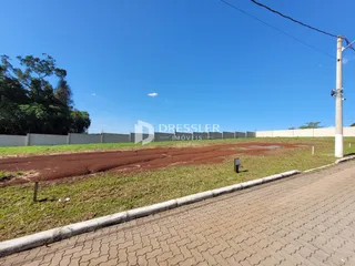 Vista externa do terreno com grama e cerca ao lado de uma estrada.