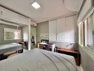 Quarto com cama e armários brancos em um imóvel no Brasil.