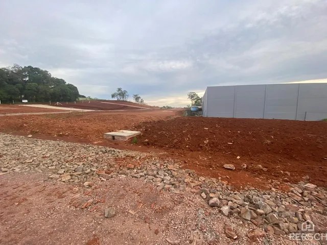 Uma vista externa de um terreno com terra vermelha e uma estrutura branca ao fundo.