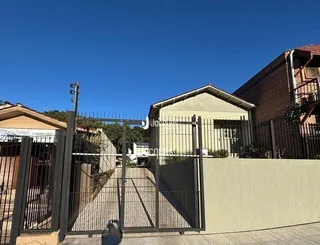 Vista da fachada de uma propriedade com cerca e portão de metal.