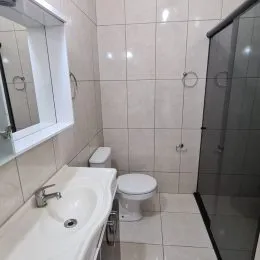 Foto interna de um banheiro com revestimento de azulejos brancos e bancada.