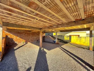 Vista de uma área externa coberta com piso de cascalho e parede de tijolos.