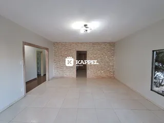Sala ampla com piso de cerâmica clara e parede de tijolos expostos.