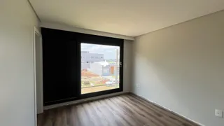 Vista interna de um cômodo com piso de madeira clara e grande janela.
