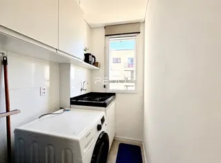 Interior de uma cozinha com armários brancos e máquina de lavar roupa.