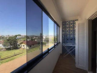 Vista da sala com grande janela para uma área residencial.