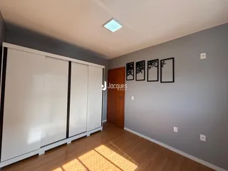Quarto com armário branco e piso de madeira clara.
