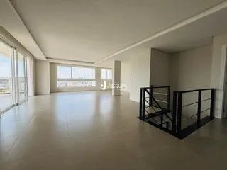 A sala de estar apresenta um piso de cerâmica claro e grandes janelas com vista externa.