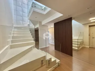 Vista de um hall com escadaria e piso de madeira em um imóvel.