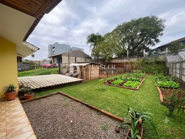 Vista externa de um jardim com gramado e cerca de madeira.