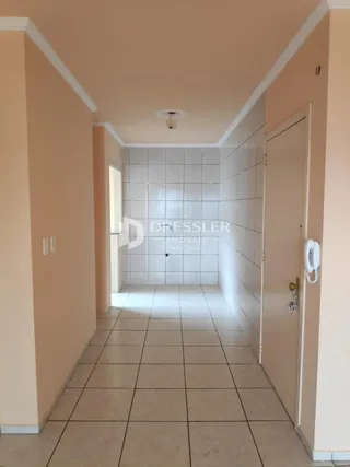Corredor interno de uma residência com piso de cerâmica clara.