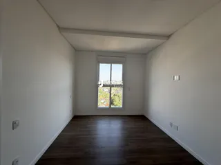 Vista de um corredor interno com piso de madeira clara.