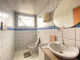Banheiro com revestimento cerâmico branco e janela.