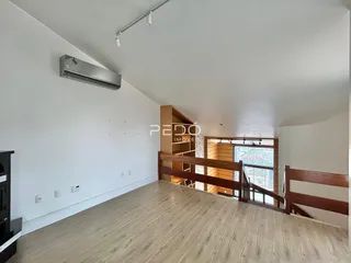 Ambiente interno com piso de madeira e parede branca.