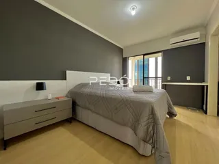 Quarto com cama grande e paredes cinzas.