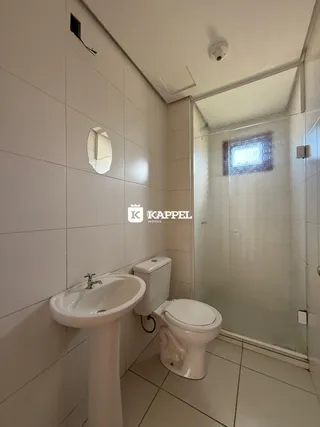 Banheiro com pia e vaso sanitário em revestimento cerâmico branco.